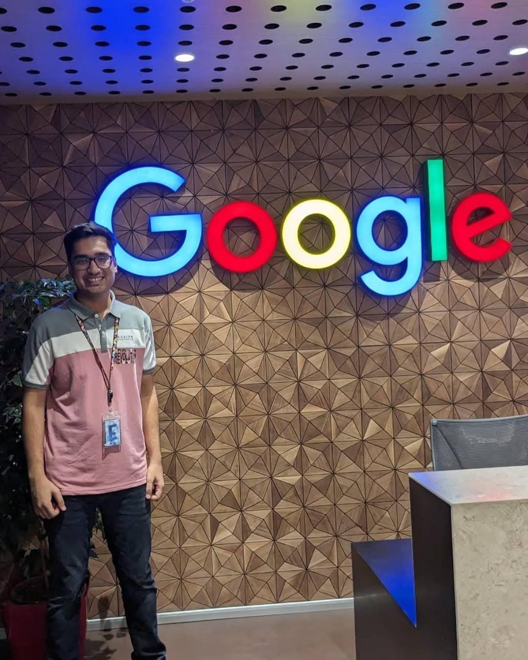 Aditya in front of the illuminated Google logo wall at the Google office in Bengaluru
